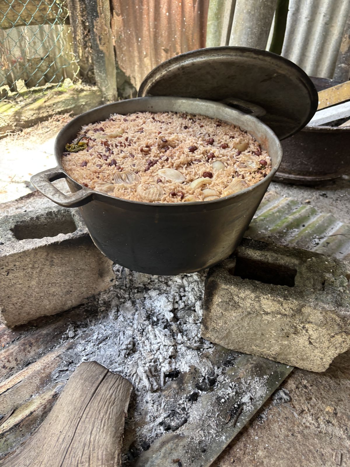 Rice and peas cooking in a dutch pot over fire